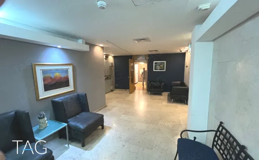 אזור המתנה עם כורסאות עור, ריצוף אבן וקיר כחול כהה במגדל יובנק UBANK