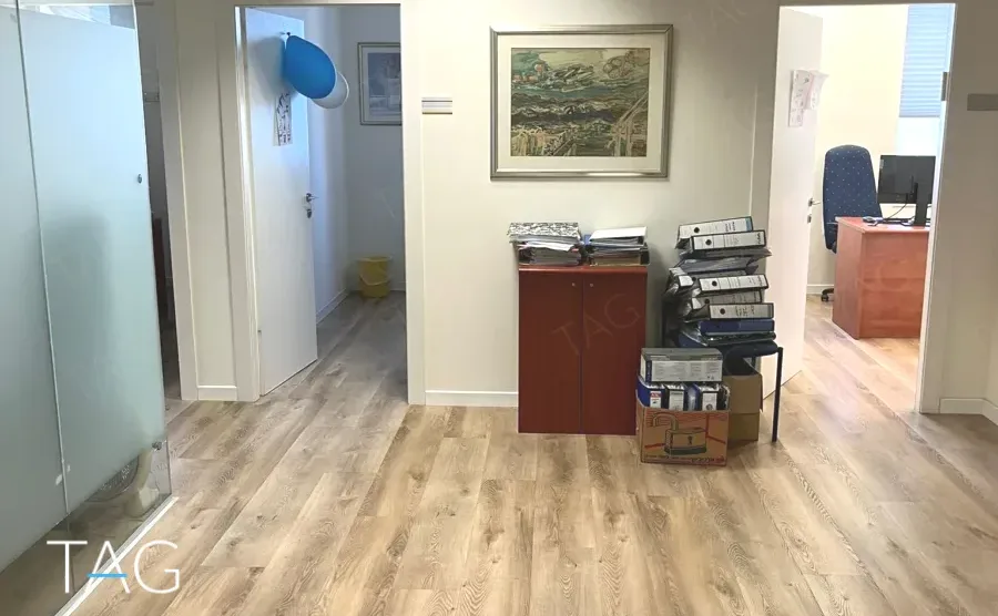 מסדרון פנימי עם ריצוף עץ בהיר, תמונות על הקיר וארכיון קלסרים במגדל יובנק UBANK