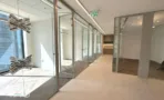 מסדרון עם חדרי זכוכית וגוף תאורה דקורטיבי במשרד במגדל אייקון