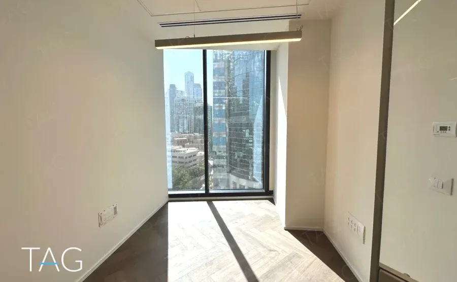 חדר עבודה עם חלון גבוה ונוף אל מגדלי האזור במגדל אייקון