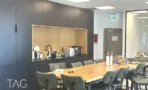 פינת אוכל עם ארונות כהים ונישת עץ מוארת במשרד 232 מ״ר במגדל אקרו