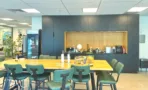 שולחן אוכל ארוך עם כיסאות ירוקים ומקרר במשרד 232 מ״ר במגדל אקרו