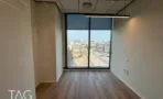 חדר עם רצפת פרקט וחלון גבוה במשרד במגדל אייקון