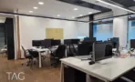 חלל עבודה פתוח במשרד בבית אמפא הרצליה עם עמדות לבנות, פרקט עץ וקורות תקרה שחורות - תג נכסים