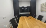 חדר ישיבות עם שולחן עץ אלון, כיסאות עור ומסך קיר, במשרד להשכרה 110 מ