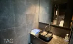 חדר שירותים עם חיפוי אריחים כהה וכיור שחור