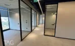 מסדרון עם חדרי זכוכית במסגרות שחורות ורצפת פרקט במגדל אייקון