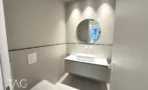 חדר רחצה במשרד במגדל אייקון עם מראה עגולה וארונית מחורצת