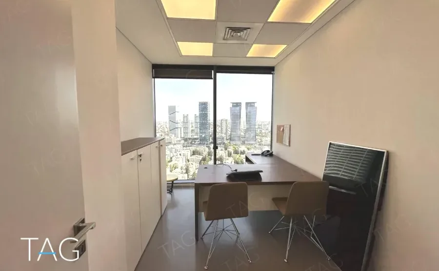 חדר עבודה עם שולחן, ארונות לבנים ונוף העיר