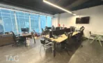 משרד להשכרה 100 מ״ר במגדל WE, אופן ספייס מרוהט עם שולחנות עבודה מול קיר חלונות