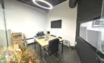 משרד להשכרה 100 מ״ר במגדל WE, חדר עבודה עם שולחן עץ ומסך תלוי על הקיר