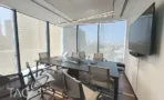 חדר ישיבות עם שולחן כהה, מסך ונוף העיר