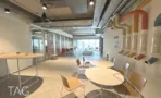 חלל אירוח משותף עם פרקט ושולחנות עגולים במרחב פלאג אנד פליי במגדל דה וינצי