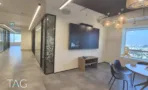 חלל עבודה עם מחיצות זכוכית שחורות ומסך קיר מול חלון עירוני, במשרד להשכרה 890 מ