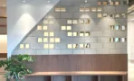 קיר בלוקים דקורטיבי משובץ לבני זכוכית ודלפק עץ במשרד במגדל אייקון