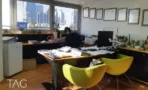 חדר עבודה עם שולחן עץ, כורסאות ליים וחלון רצועה שצופה אל מגדלי תל אביב, במשרד בבית מרכז אשדר - תג נכסים