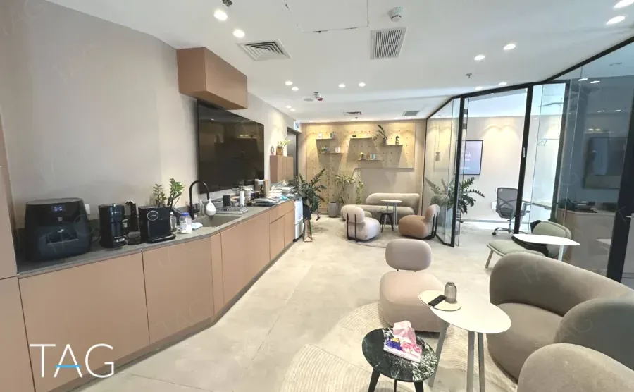 מטבח ולאונג' עם ארונות בגוון חול וספות עגולות במשרד 148 מ״ר במגדל אקרו