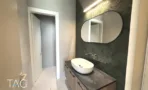 חדר רחצה מעוצב במשרד במגדל אייקון, אריחי דגם אדרה ירוקים ומראה אובלית