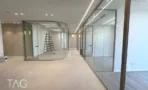 מסדרון עם קיר זכוכית מעוגל וחדרי עבודה במגדל אייקון