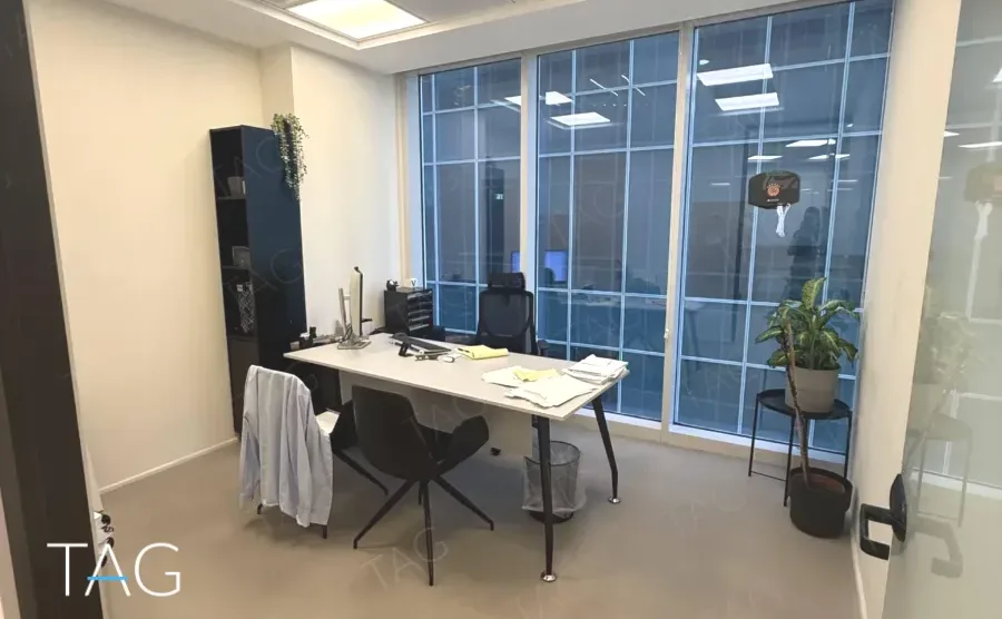 משרד להשכרה 73 מ״ר במגדל WE, חדר עבודה עם שולחן ומחשב מול קיר חלונות פנימי