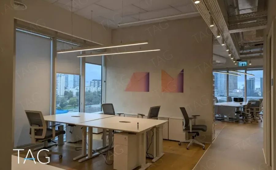 משרד להשכרה 450 מ״ר במגדל WE, חלל פתוח עם עמדות עבודה ונוף עירוני מהחלונות