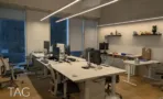 משרד להשכרה 450 מ״ר במגדל WE, חדר עבודה עם שולחנות ומסכים מול חלונות גדולים