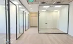 משרד בגמר מלא במגדל אייקון, פרקט בהיר ומחיצות זכוכית במסגרות שחורות
