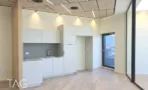 מטבחון לבן ליד עמוד עץ במשרד במגדל אייקון, ודלת יציאה למרפסת
