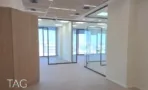 קיר מחופה עץ ומחיצות זכוכית במשרד במגדל אייקון מול נוף עירוני