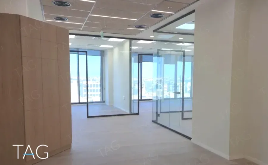 קיר מחופה עץ ומחיצות זכוכית במשרד במגדל אייקון מול נוף עירוני