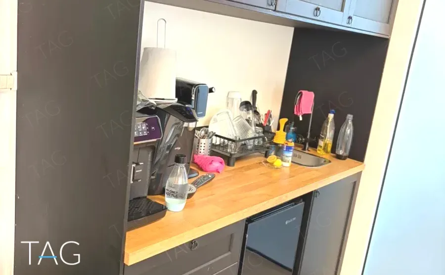 מטבחון עם ארונות אפורים ומשטח עץ במשרד להשכרה 70 מ