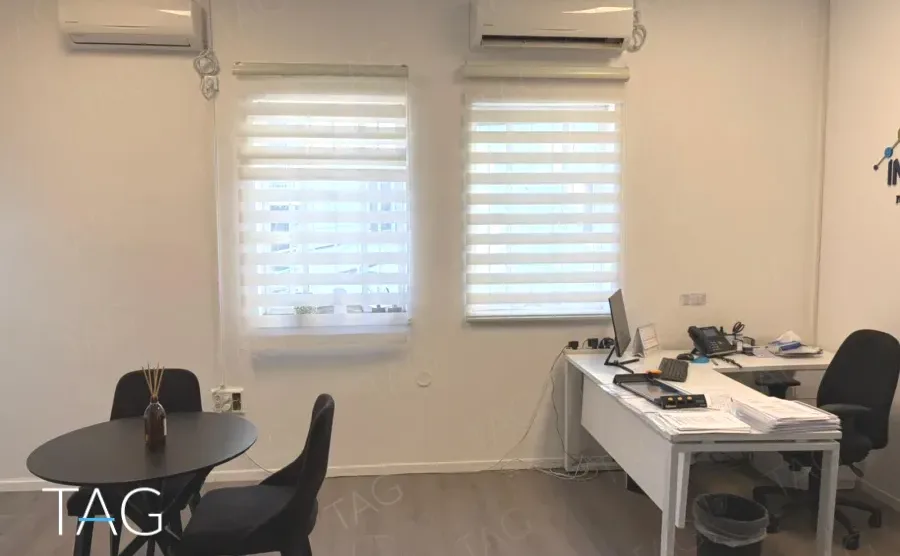 חדר עבודה עם שולחן עגול ווילונות זברה במשרד להשכרה בתל אביב - תג נכסים