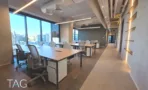 חלל עבודה פתוח במגדל אייקון עם שולחן ישיבות וקיר דקורטיבי בגוון זהב