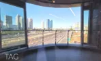 מרפסת מעוגלת במגדל אייקון עם מעקה מתכת, נוף אל נתיבי איילון והמסילה