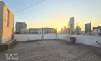 דק העץ שעל הגג מול קו הרקיע של תל אביב בשעת שקיעה - תג נכסים