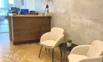 עמדת קבלה עם דלפק עץ, קיר בטון וכורסאות בהירות