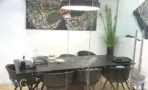 חדר ישיבות עם שולחן כהה, תמונת קיר צבעונית וצמח