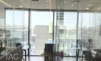 חדר עבודה מזוגג עם נוף העיר וקיר בטון