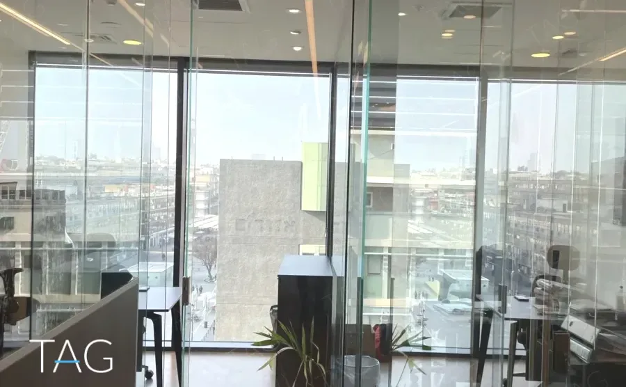 חדר עבודה מזוגג עם נוף העיר וקיר בטון