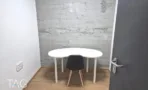 חדר צדדי במשרד להשכרה ברחוב אחד העם תל אביב, שולחן לבן מעוגל מול קיר לבנים חשוף - תג נכסים