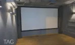 חדר הקרנות במשרד להשכרה ברחוב אחד העם תל אביב, מסך רחב על קיר כחול כהה ורצפת עץ - תג נכסים