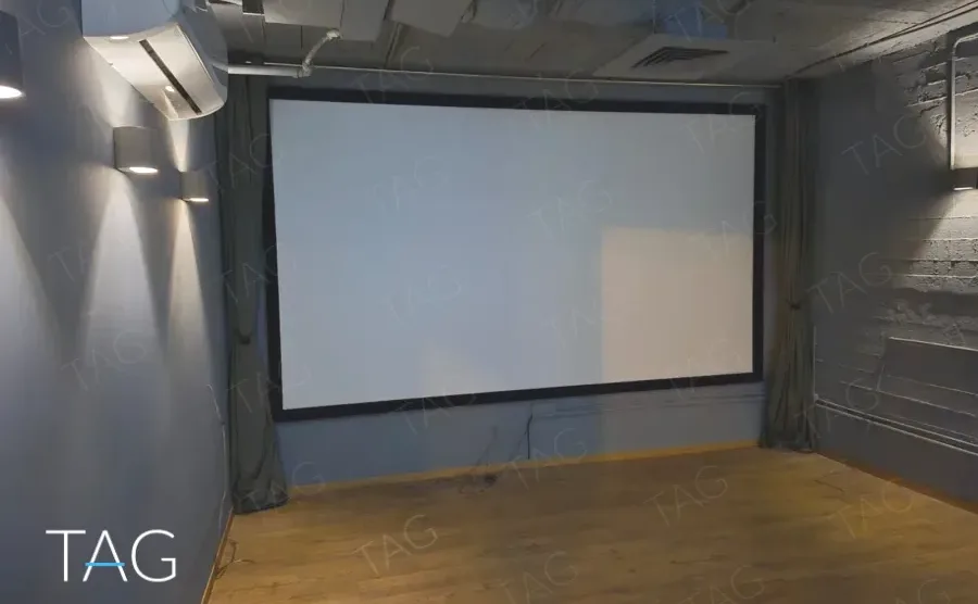 חדר הקרנות במשרד להשכרה ברחוב אחד העם תל אביב, מסך רחב על קיר כחול כהה ורצפת עץ - תג נכסים