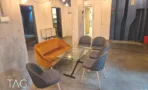 חלל פתוח במשרד להשכרה ברחוב אחד העם תל אביב, כורסה כתומה, שולחן זכוכית ועמודי בטון - תג נכסים