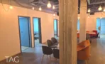 מעבר פנימי במשרד להשכרה ברחוב אחד העם תל אביב, נורות תלויות על כבלים ופינת ישיבה בקצה - תג נכסים