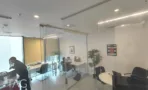 משרד קומפקטי עם מחיצות זכוכית, שולחן וצמחייה
