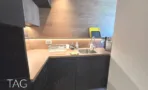 מטבחון עם ארונות עץ עליונים, בסיס כהה וכיור