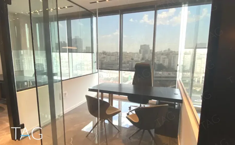 משרד למכירה 75 מ״ר במגדל WE, חדר פינתי מזוגג עם שולחן עבודה ונוף עירוני רחב