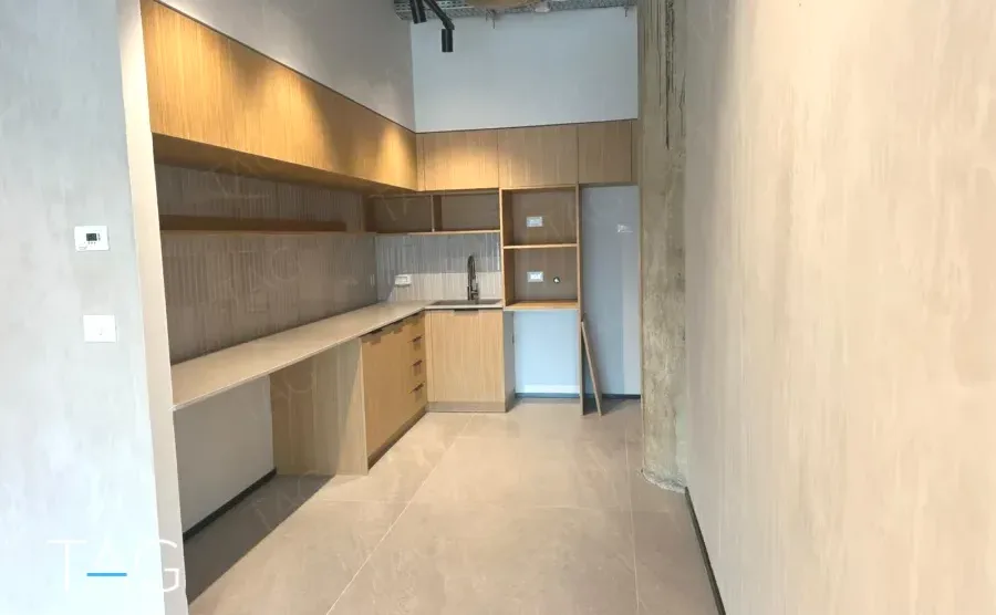 מטבח משרדי בACRO BUSINESS CAMPUS עם חיפוי עץ, מדפים פתוחים ומשטח ארוך - תג נכסים