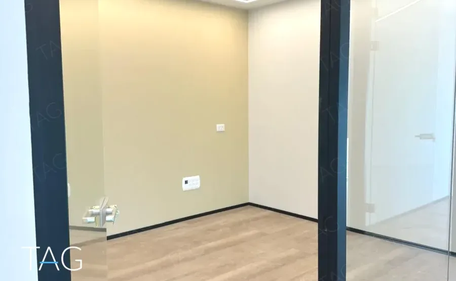 חדר בACRO BUSINESS CAMPUS עם קירות בהירים, מחיצות זכוכית ופרקט - תג נכסים
