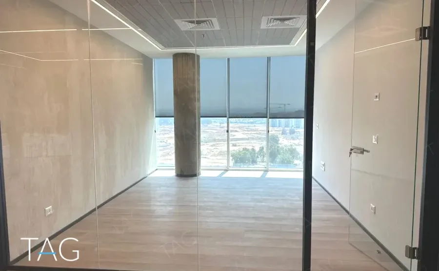 חלל משרדי בACRO BUSINESS CAMPUS עם קיר טיח מרוח, עמוד בטון וחזית זכוכית - תג נכסים